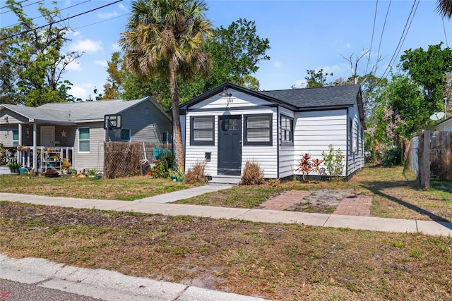 bungalow-style home featuring entry steps, fence, and a front lawn