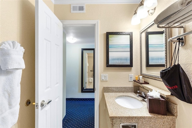 bathroom with visible vents, crown molding, and vanity