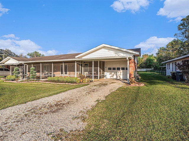 view of front facade featuring a garage, brick siding, a sunroom, a front lawn, and gravel driveway