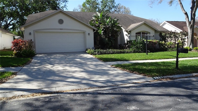 single story home featuring a garage, driveway, a front yard, and stucco siding