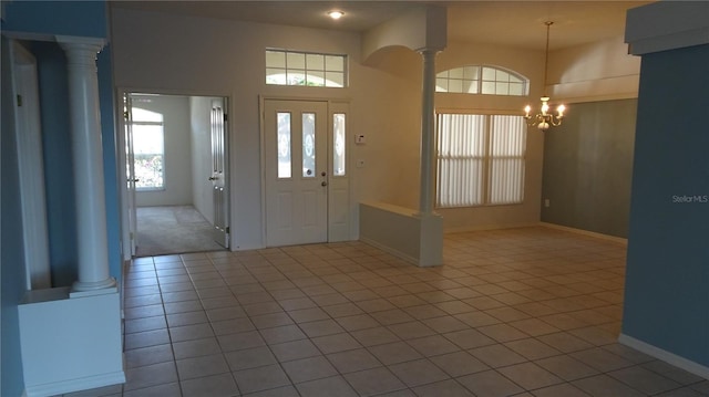 foyer featuring baseboards, decorative columns, an inviting chandelier, and tile patterned floors