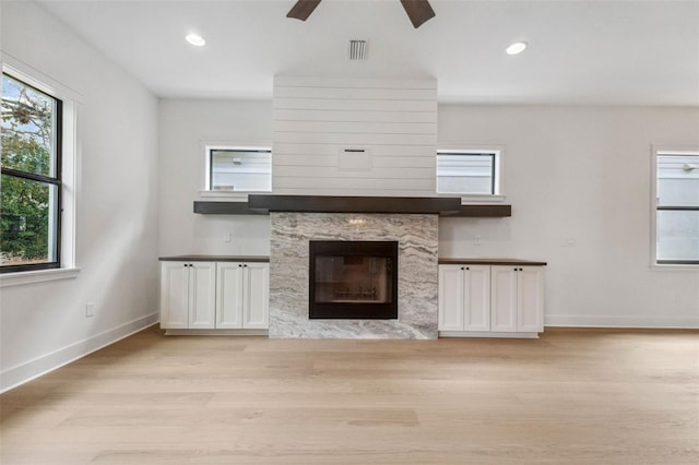 unfurnished living room featuring light wood-type flooring, a fireplace, baseboards, and recessed lighting