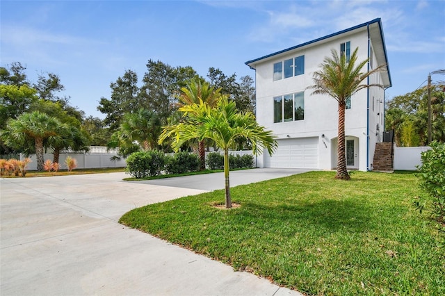 view of front of home with a garage, concrete driveway, stucco siding, fence, and a front yard