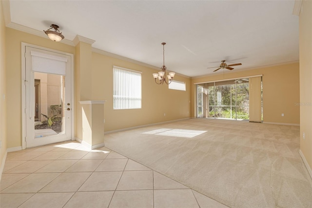 carpeted spare room with ornamental molding, plenty of natural light, tile patterned flooring, and baseboards