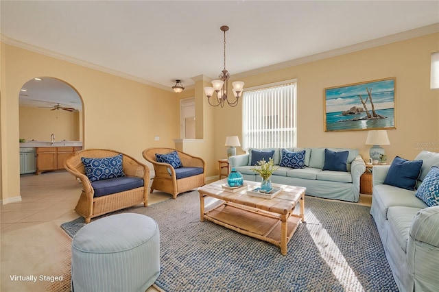 living room with light tile patterned floors, baseboards, arched walkways, crown molding, and ceiling fan with notable chandelier