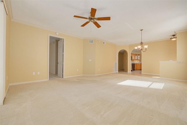 spare room featuring light carpet, visible vents, arched walkways, and crown molding