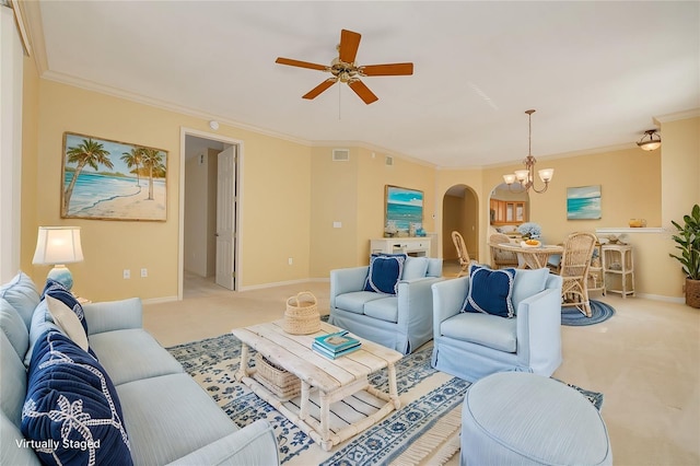 carpeted living area with arched walkways, ceiling fan with notable chandelier, visible vents, baseboards, and ornamental molding