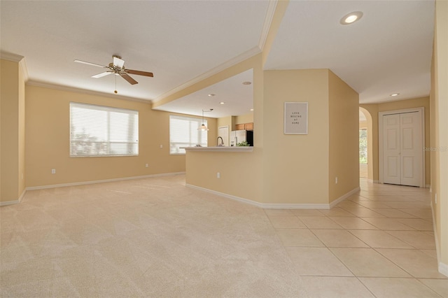 empty room featuring baseboards, arched walkways, light colored carpet, and crown molding