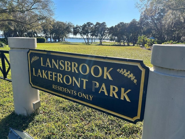 community sign with a water view and a lawn