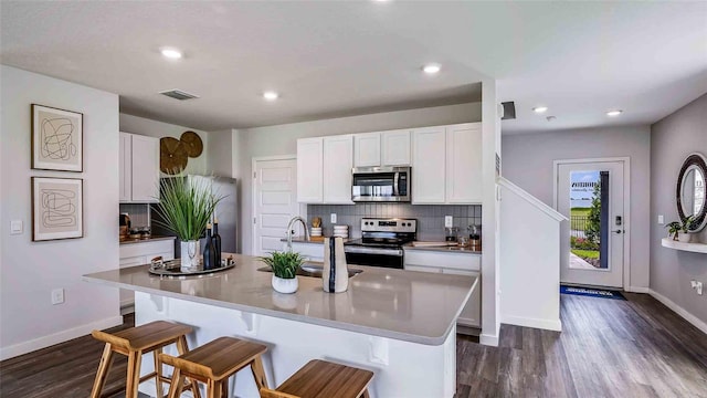 kitchen with stainless steel appliances, white cabinetry, decorative backsplash, and a kitchen bar