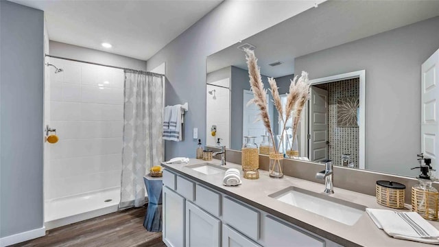 bathroom featuring tiled shower, a sink, and wood finished floors