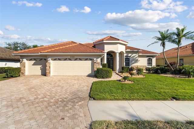 mediterranean / spanish-style house featuring a garage, a tile roof, decorative driveway, a front lawn, and stucco siding