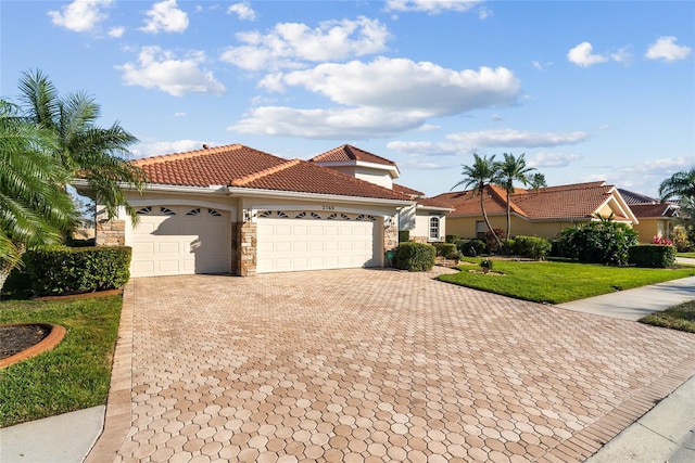 view of front facade with a garage, a tile roof, stone siding, decorative driveway, and a front yard