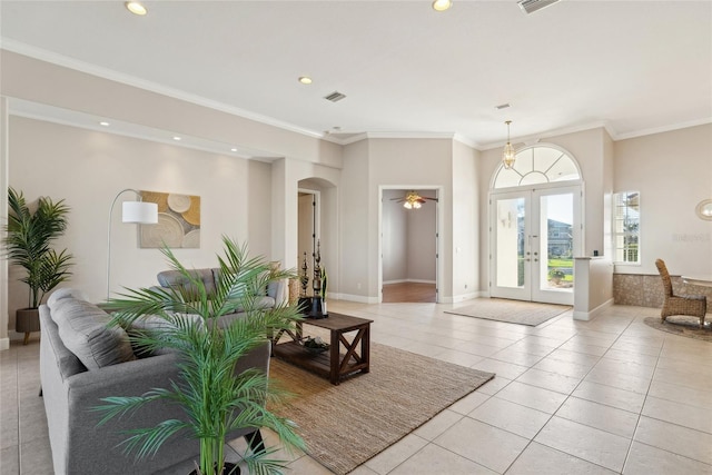 living area with light tile patterned floors, arched walkways, crown molding, and french doors