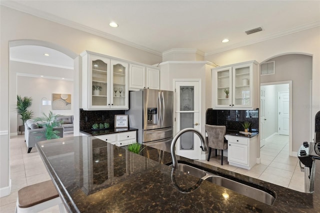 kitchen featuring decorative backsplash, visible vents, stainless steel refrigerator with ice dispenser, and a sink