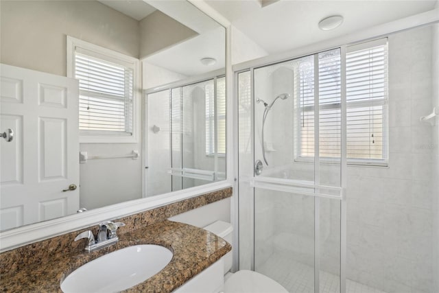 bathroom featuring toilet, a shower stall, and vanity