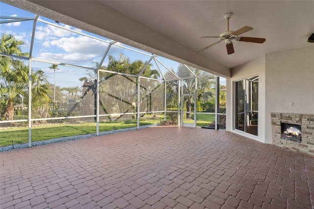 unfurnished sunroom featuring ceiling fan and an outdoor stone fireplace