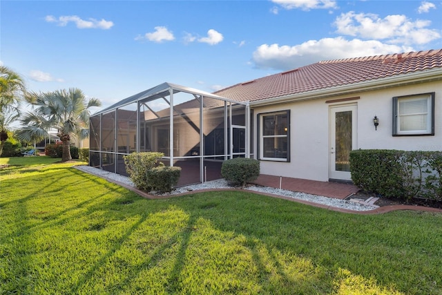 back of house featuring a tiled roof, a lawn, a lanai, and stucco siding