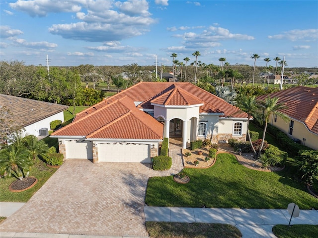 mediterranean / spanish house featuring driveway, stone siding, a garage, and a tiled roof