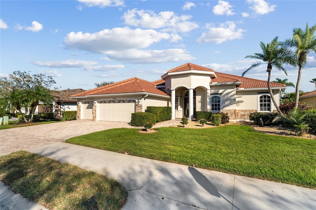 mediterranean / spanish-style house with stucco siding, a front yard, a garage, driveway, and a tiled roof