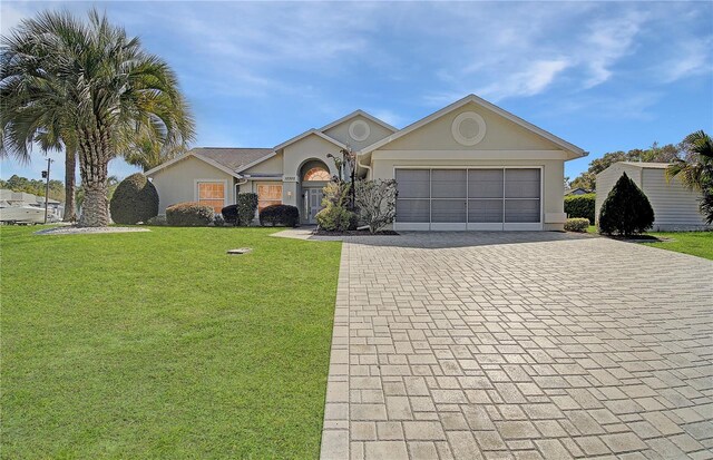 single story home with a front lawn, decorative driveway, an attached garage, and stucco siding
