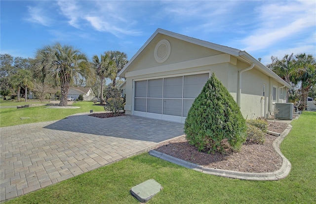 garage featuring central air condition unit and decorative driveway