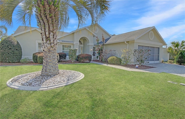 view of front of home featuring decorative driveway, a front lawn, an attached garage, and stucco siding
