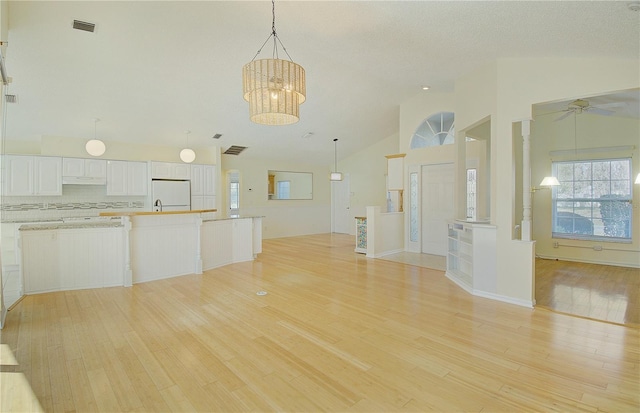 kitchen with light wood-style flooring, freestanding refrigerator, white cabinetry, ceiling fan with notable chandelier, and open floor plan