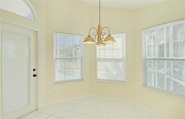 unfurnished dining area with light tile patterned floors, baseboards, lofted ceiling, and an inviting chandelier