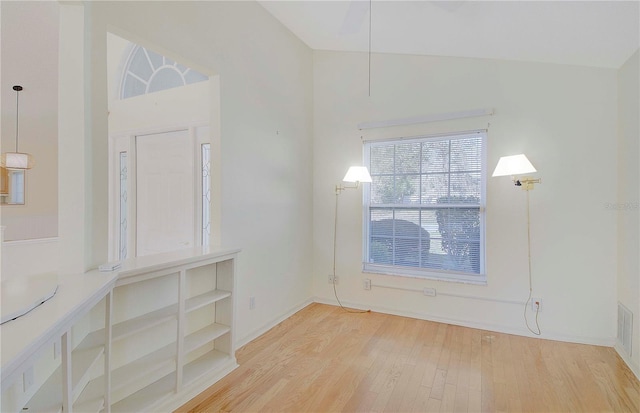 empty room featuring vaulted ceiling, baseboards, and wood finished floors