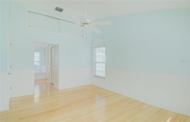 unfurnished room featuring a wealth of natural light, a wainscoted wall, and wood finished floors