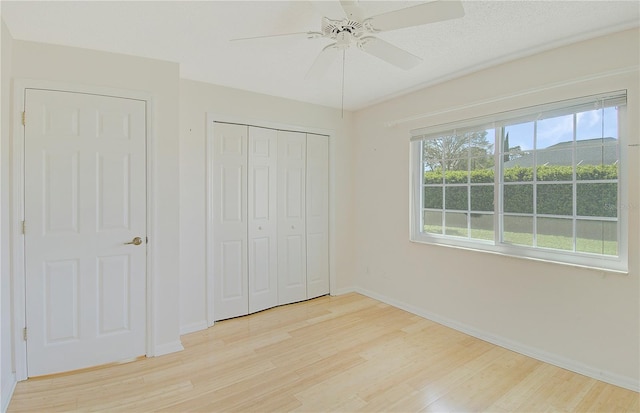 unfurnished bedroom with a closet, baseboards, light wood-style floors, and a ceiling fan