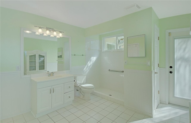 bathroom featuring visible vents, a wainscoted wall, toilet, walk in shower, and vanity