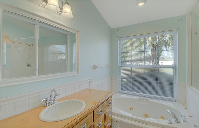 bathroom with a wainscoted wall, a tub with jets, vanity, and vaulted ceiling