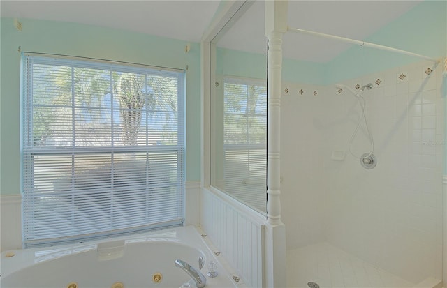 bathroom featuring a wainscoted wall, a jetted tub, and a tile shower