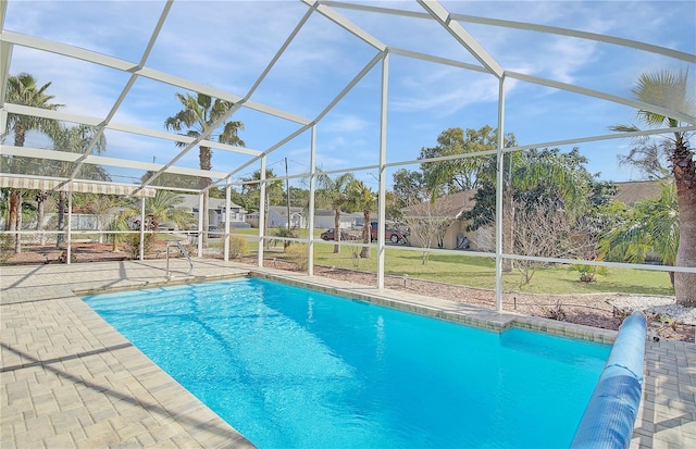 outdoor pool featuring glass enclosure, a lawn, and a patio