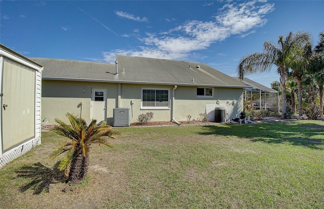 back of property featuring a yard, central AC unit, a lanai, and stucco siding