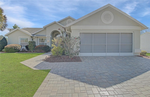ranch-style house featuring a front yard, decorative driveway, an attached garage, and stucco siding