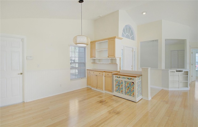 kitchen featuring a wainscoted wall, light brown cabinetry, open shelves, light wood-style floors, and hanging light fixtures