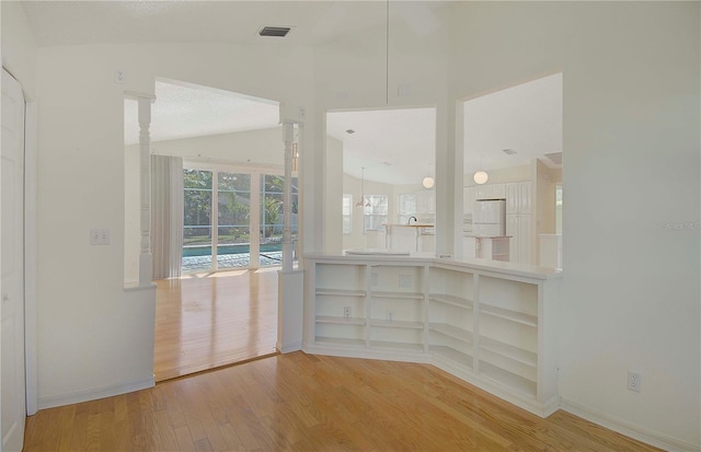 unfurnished room featuring visible vents, wood finished floors, baseboards, and vaulted ceiling