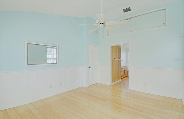 unfurnished room with visible vents, wood finished floors, and a wainscoted wall