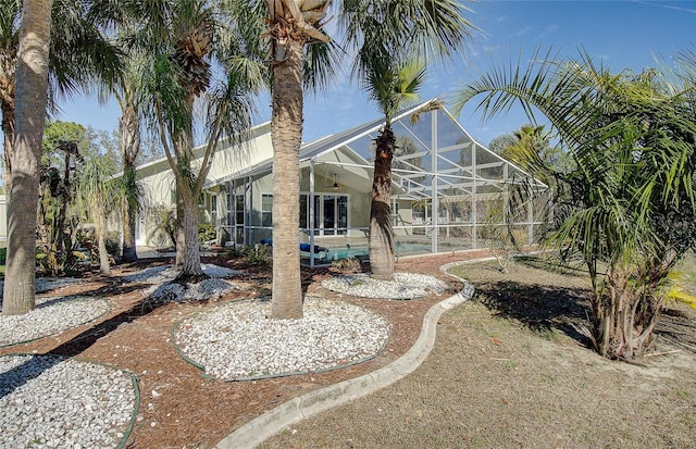 back of property with an outdoor pool and glass enclosure