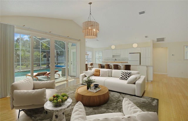 living room featuring light wood-type flooring, visible vents, and a healthy amount of sunlight
