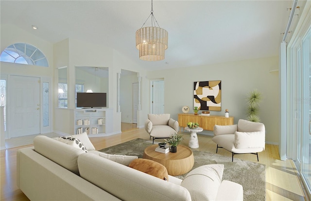 living room featuring a notable chandelier, high vaulted ceiling, baseboards, and wood finished floors