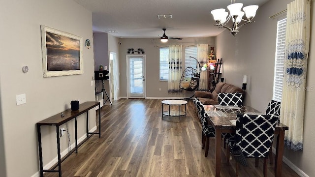 living area featuring visible vents, ceiling fan with notable chandelier, baseboards, and wood finished floors