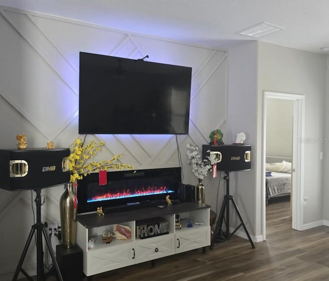 living room with visible vents, baseboards, a lit fireplace, and wood finished floors