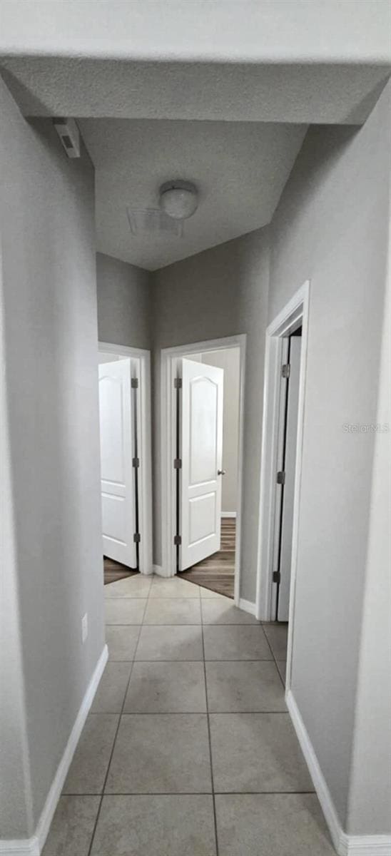 hallway featuring light tile patterned floors and baseboards