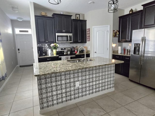 kitchen with light tile patterned floors, appliances with stainless steel finishes, light stone counters, and a sink