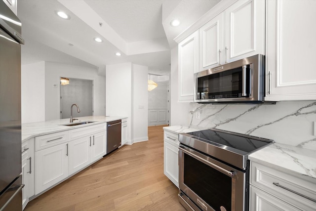 kitchen with white cabinets, appliances with stainless steel finishes, light wood-style floors, a sink, and recessed lighting