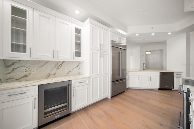 kitchen with beverage cooler, stainless steel built in fridge, a sink, and white cabinetry